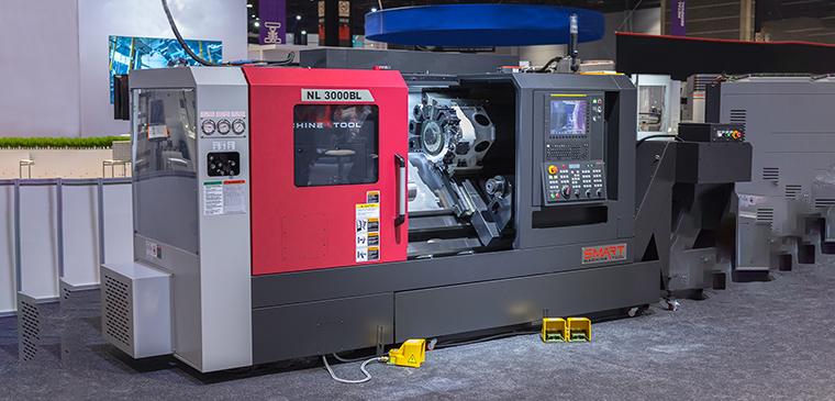 Токарний верстат з ЧПК SMART Machine Tool NL 3000BL сіро-чорного кольору з червоними захисними дверцятами робочої зони та панеллю керування на виставковому стенді
